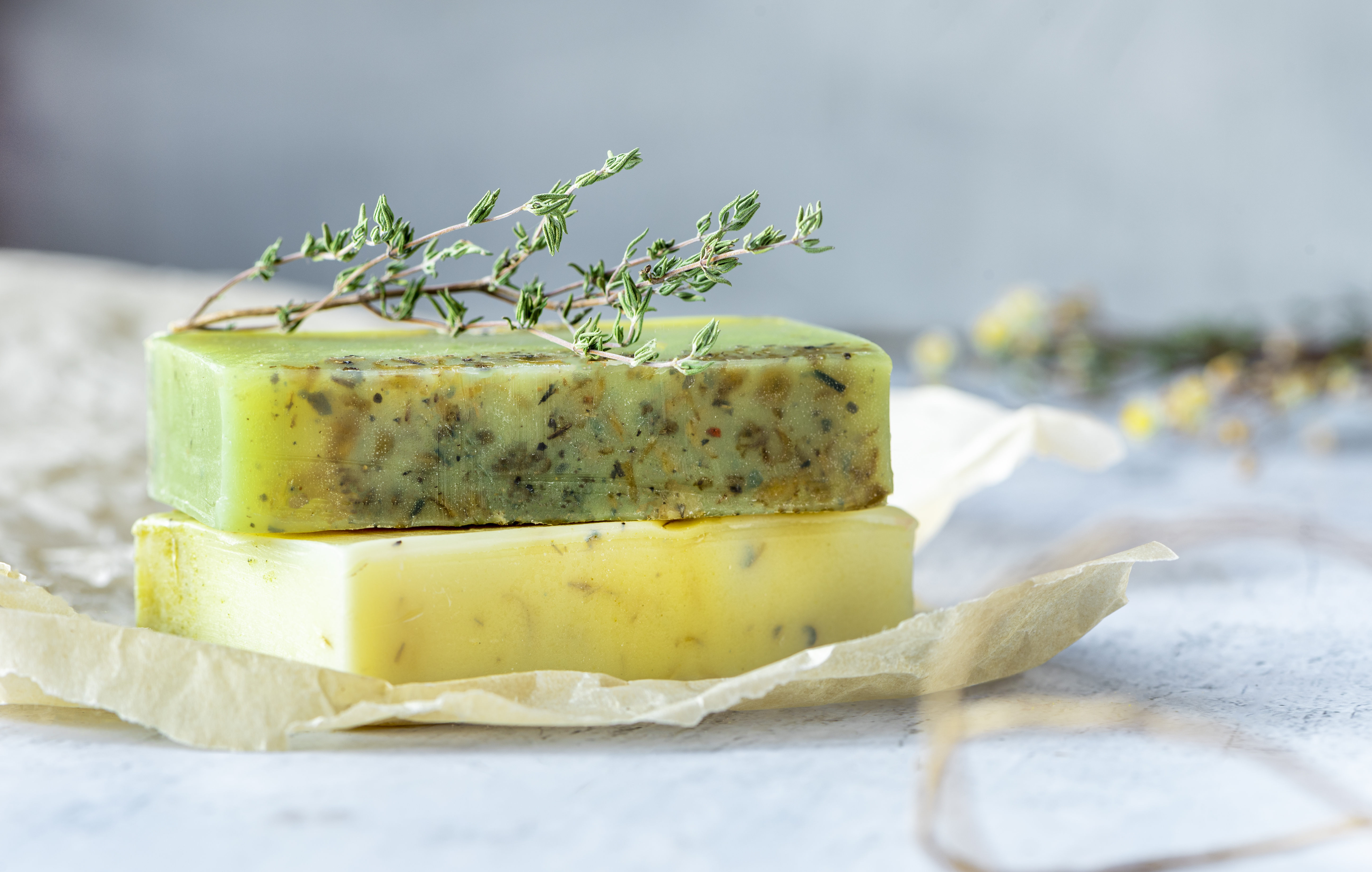 Herbal green handmade soap and dry herbs on the table, grey background, selective focus, copy space.